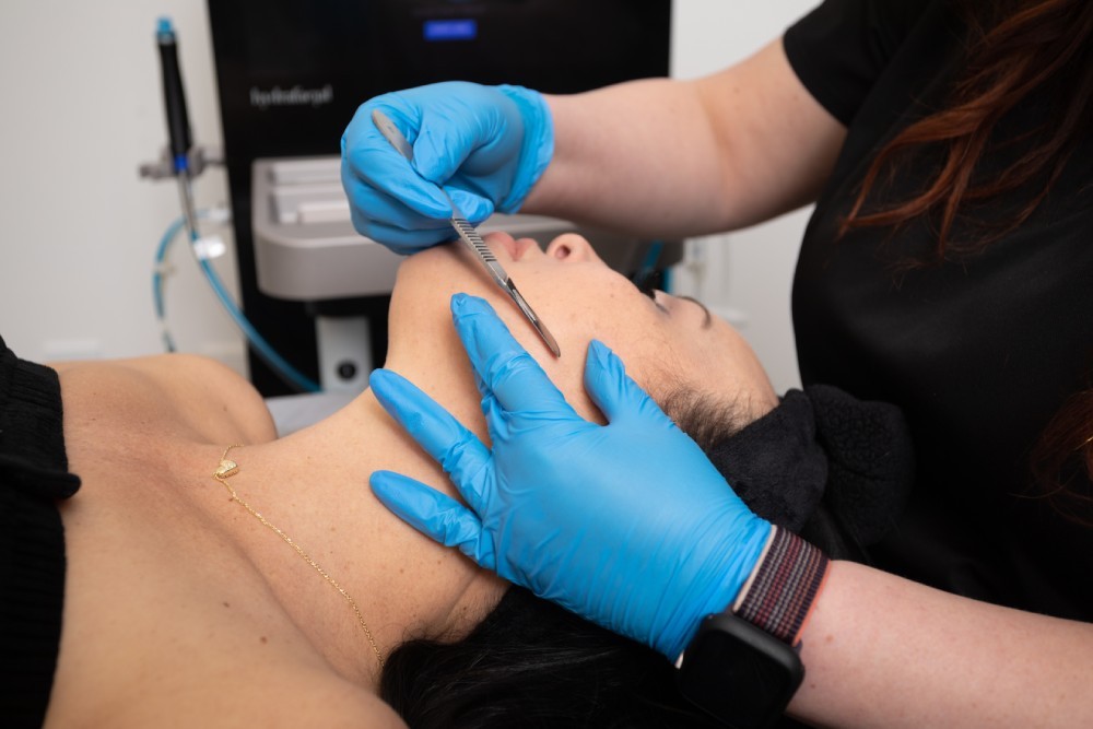 Med spa aesthetician performing facial treatment with a tool.