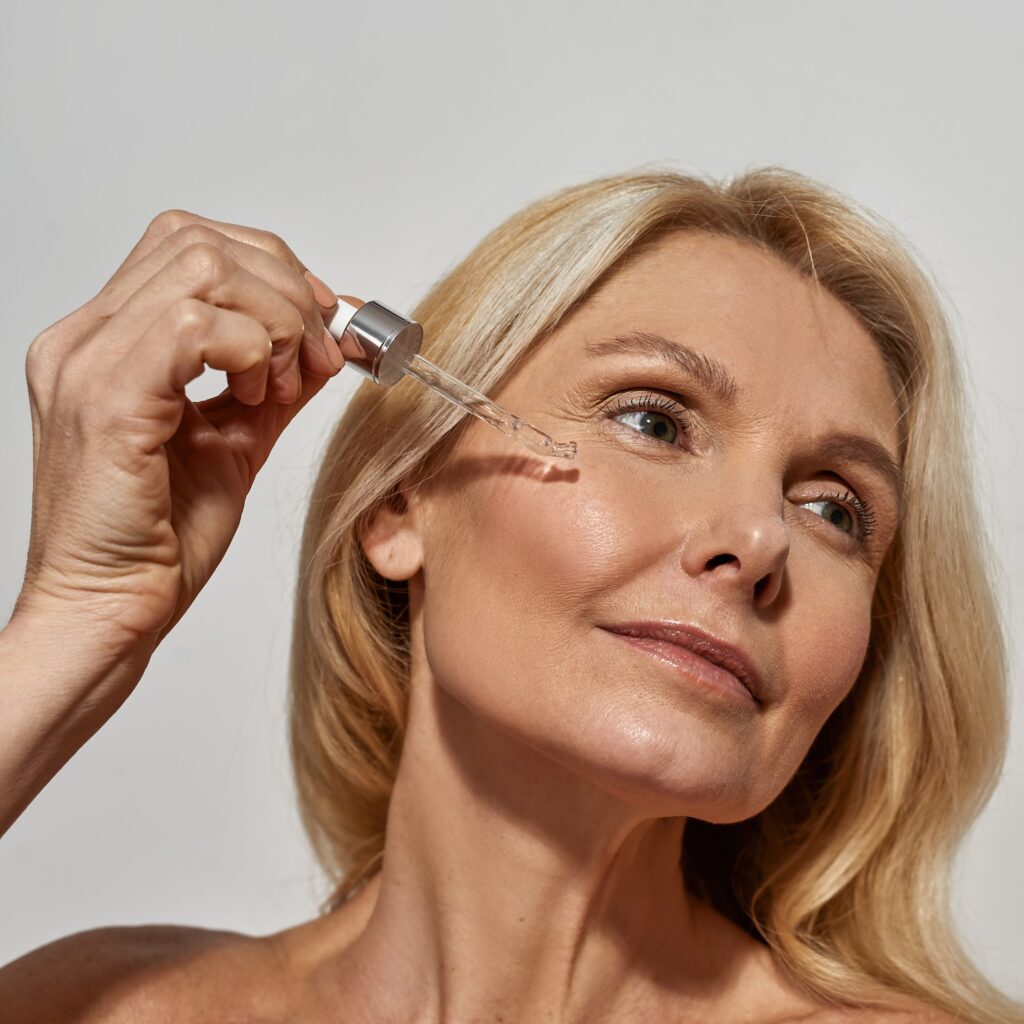 woman applying facial serum with a dropper near her cheek
