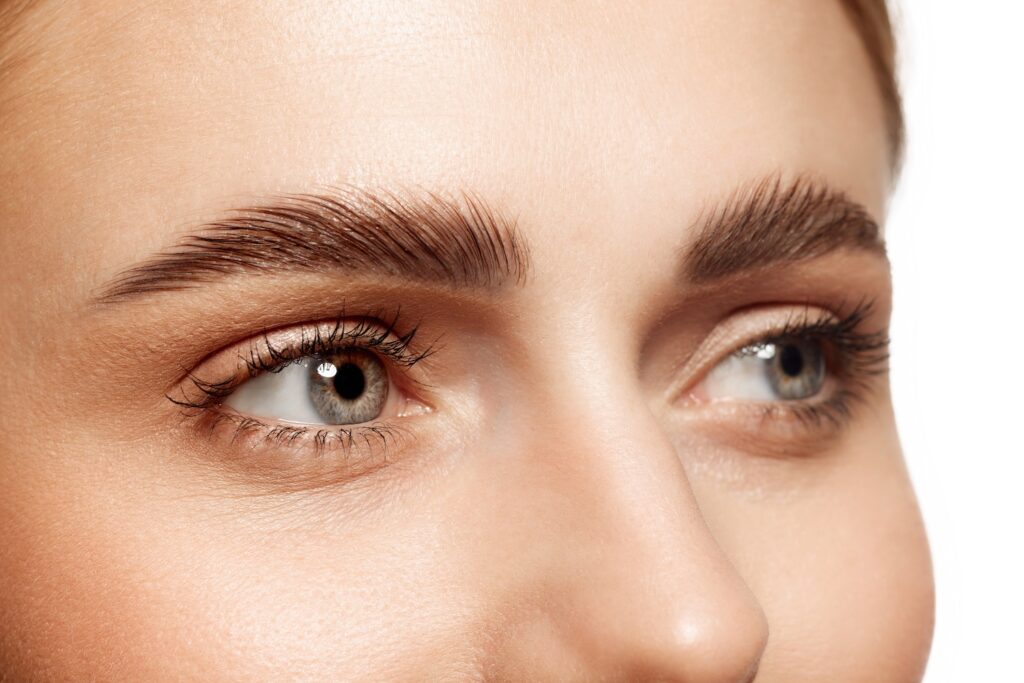 close-up view of a person’s eyes and natural eyebrows with visible lashes and skin texture