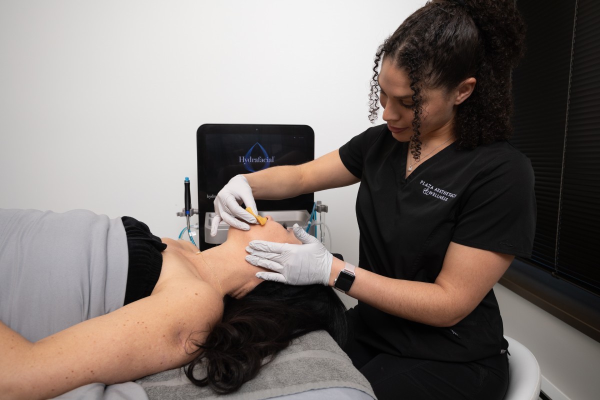 Provider applies a solution to a patient’s face while the patient lies on a treatment bed