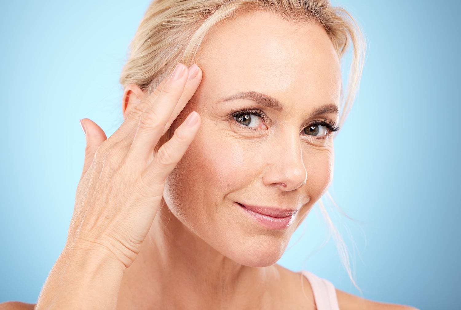 woman touching the side of her forehead near her temple