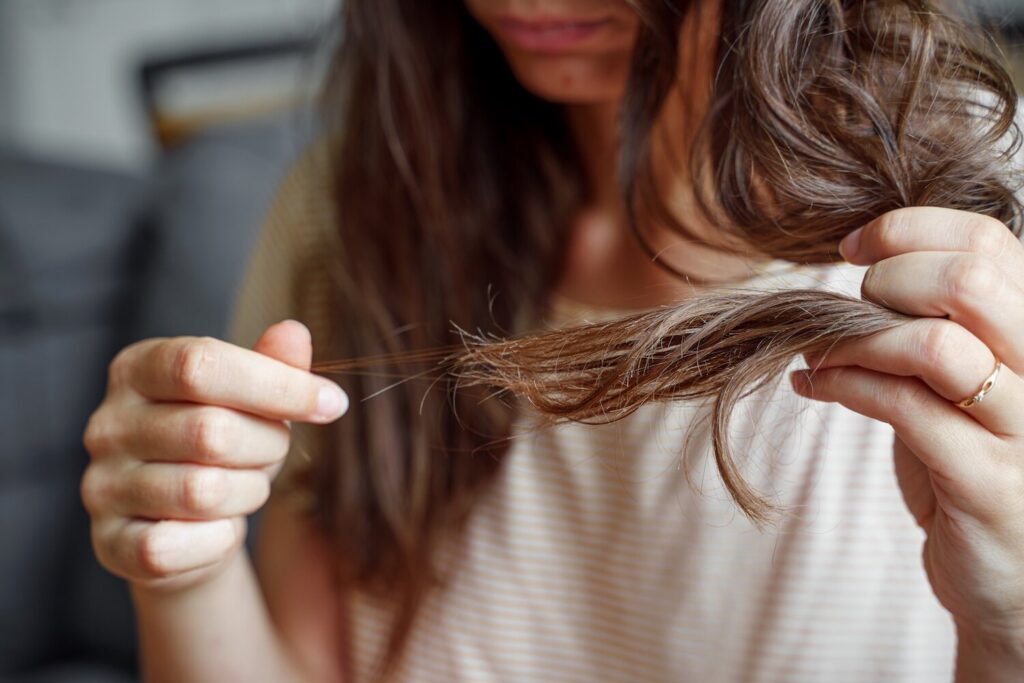 man looking in the mirror and checking his hairline with his hand, showing concern about hair thinning