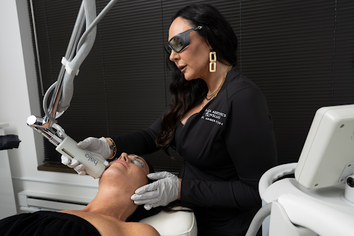 Provider wearing protective eyewear performs a laser treatment on a person lying on a treatment bed.
