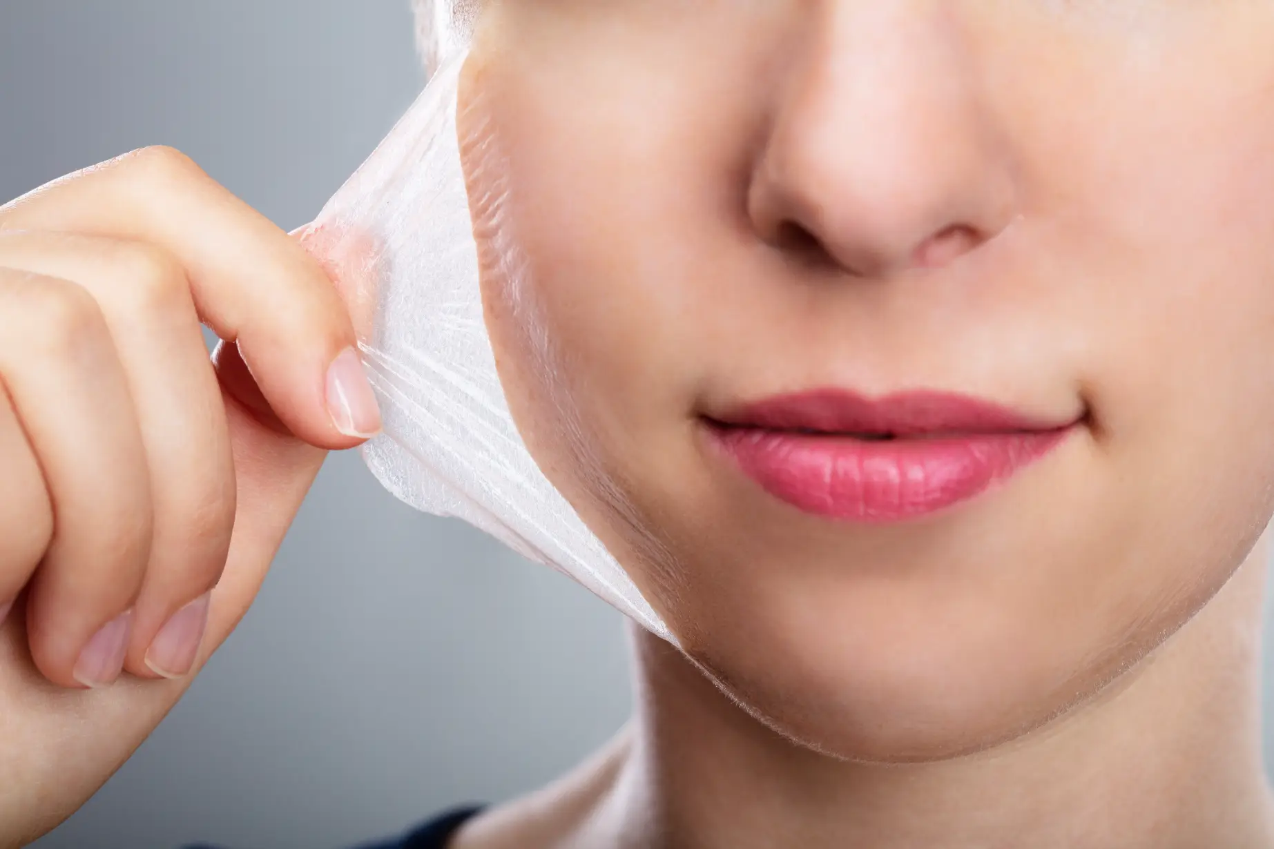 Close-up of person peeling off exfoliating mask from cheek