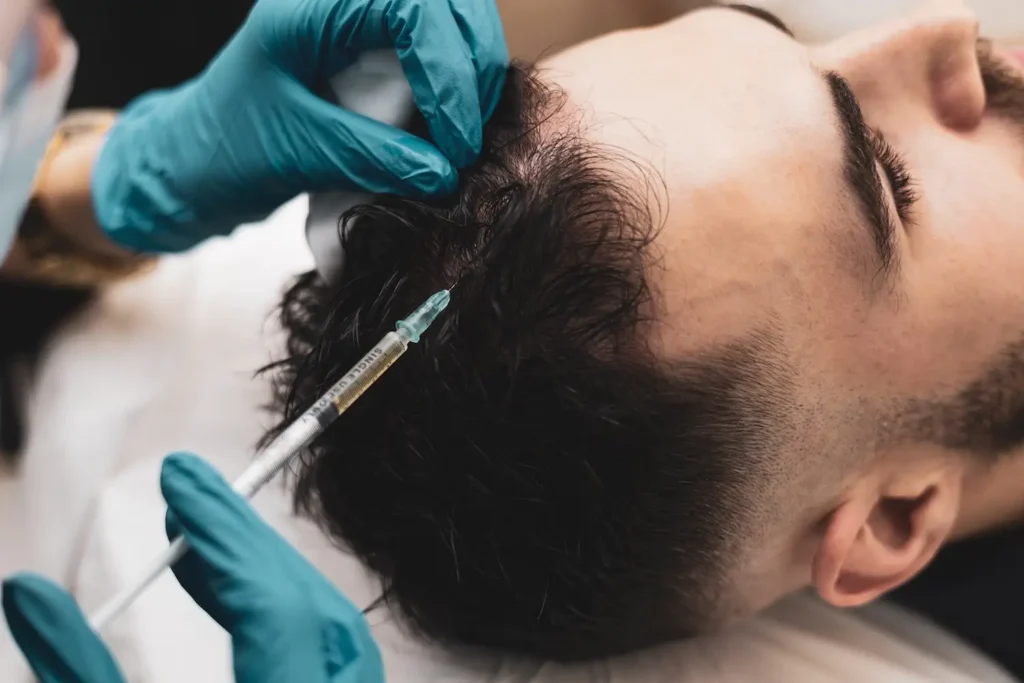 Gloved hands inject liquid into the scalp of a man lying on his side