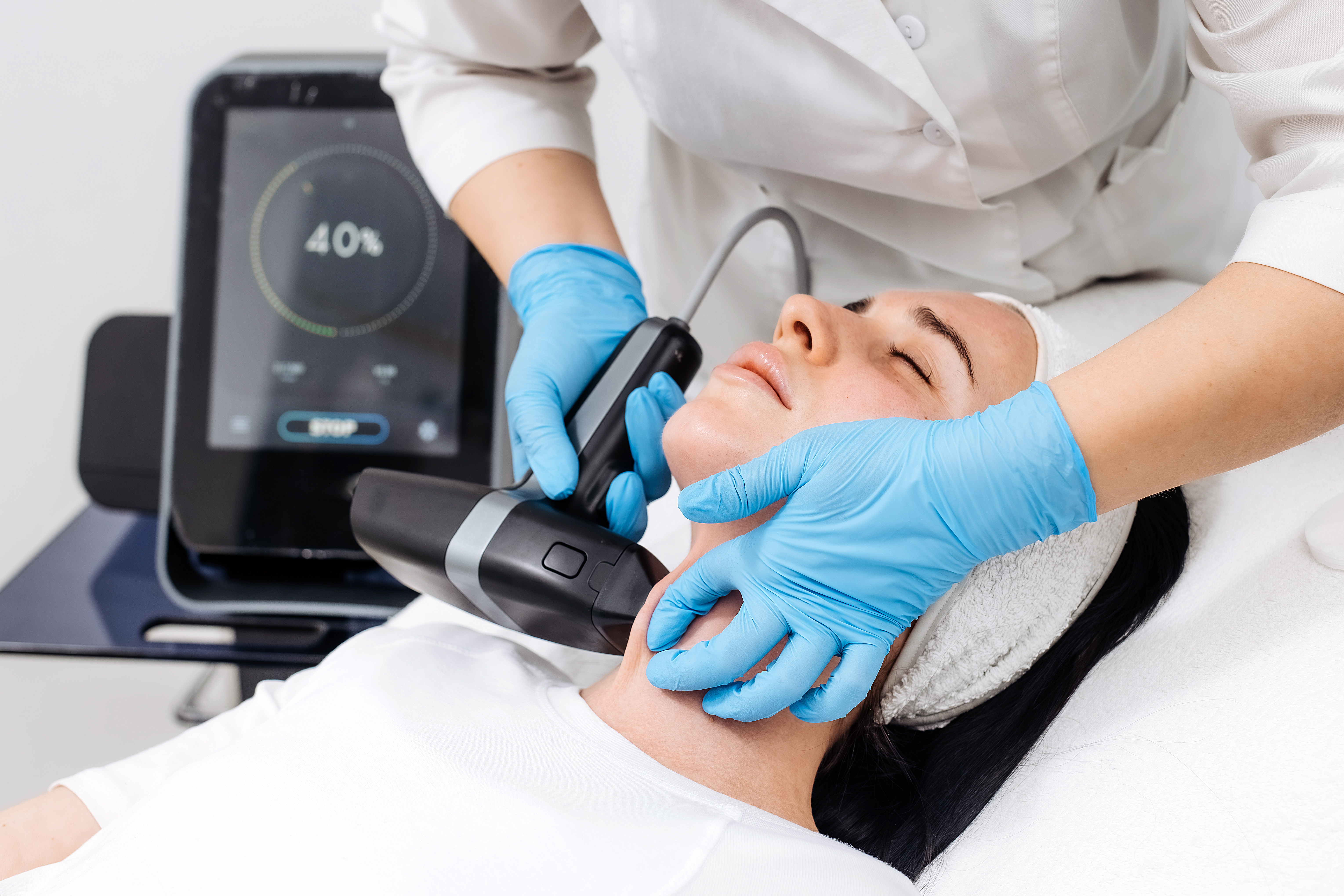 Device applied to woman’s neck during noninvasive skin tightening procedure