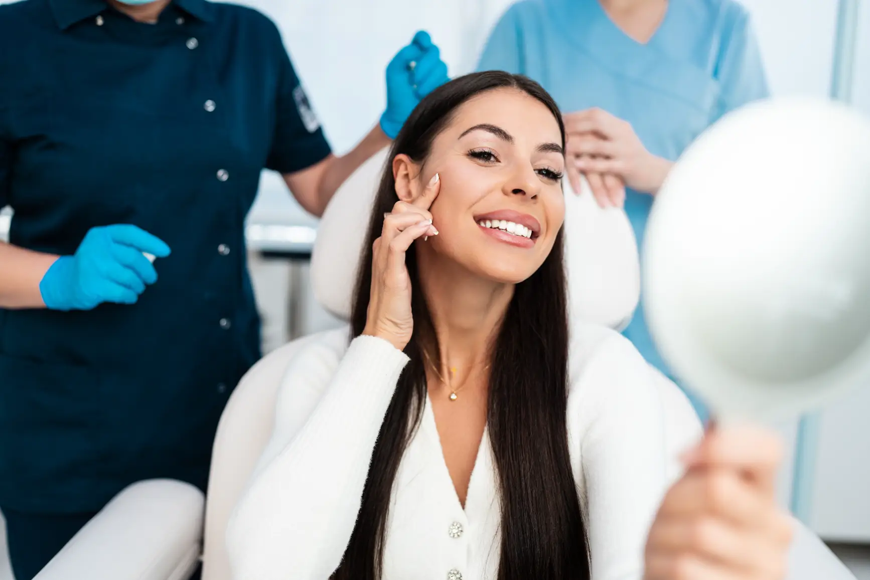 Woman smiling at her reflection during a med spa consultation with staff in background