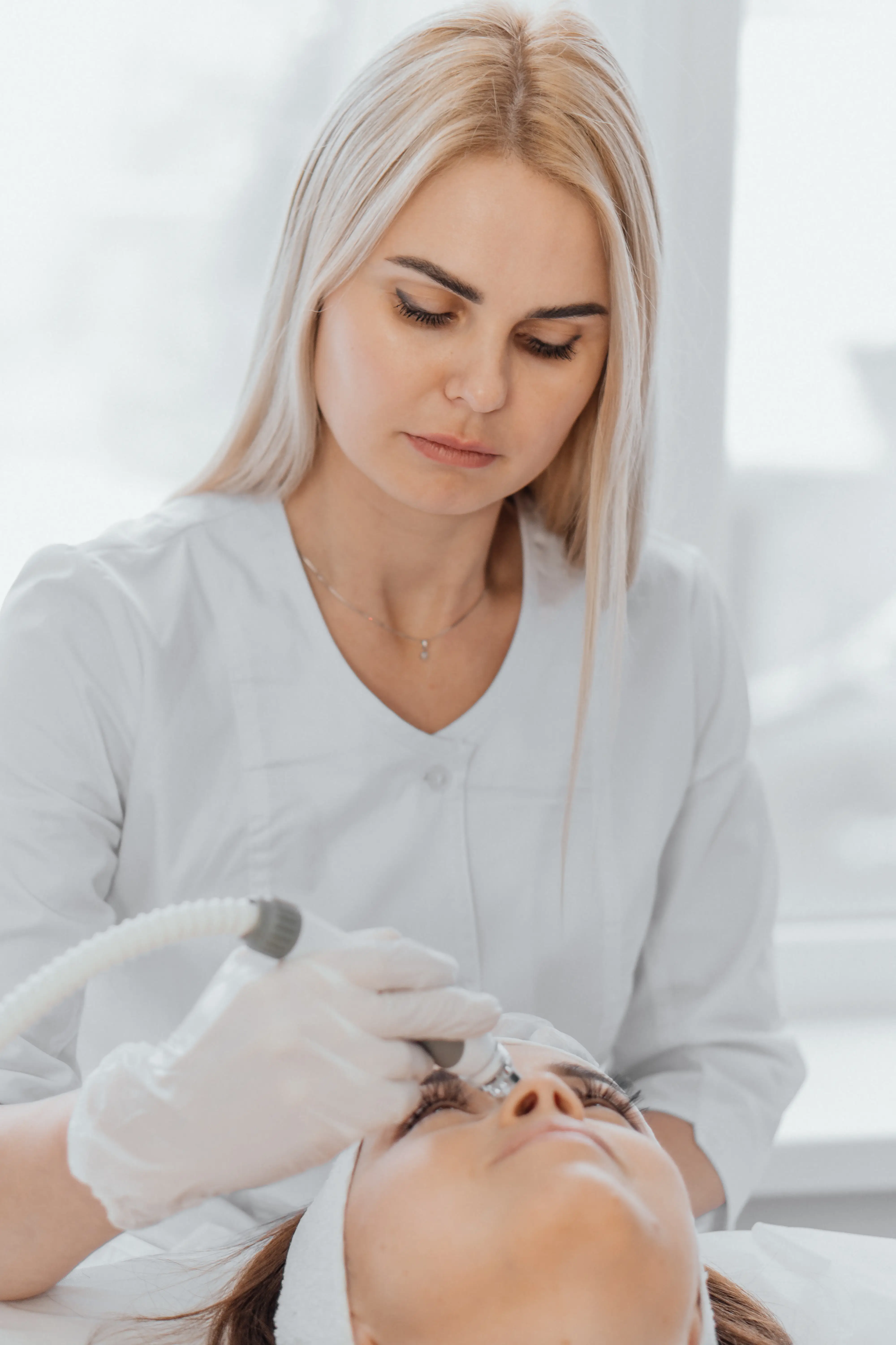 Practitioner using microneedling device on woman’s face during treatment