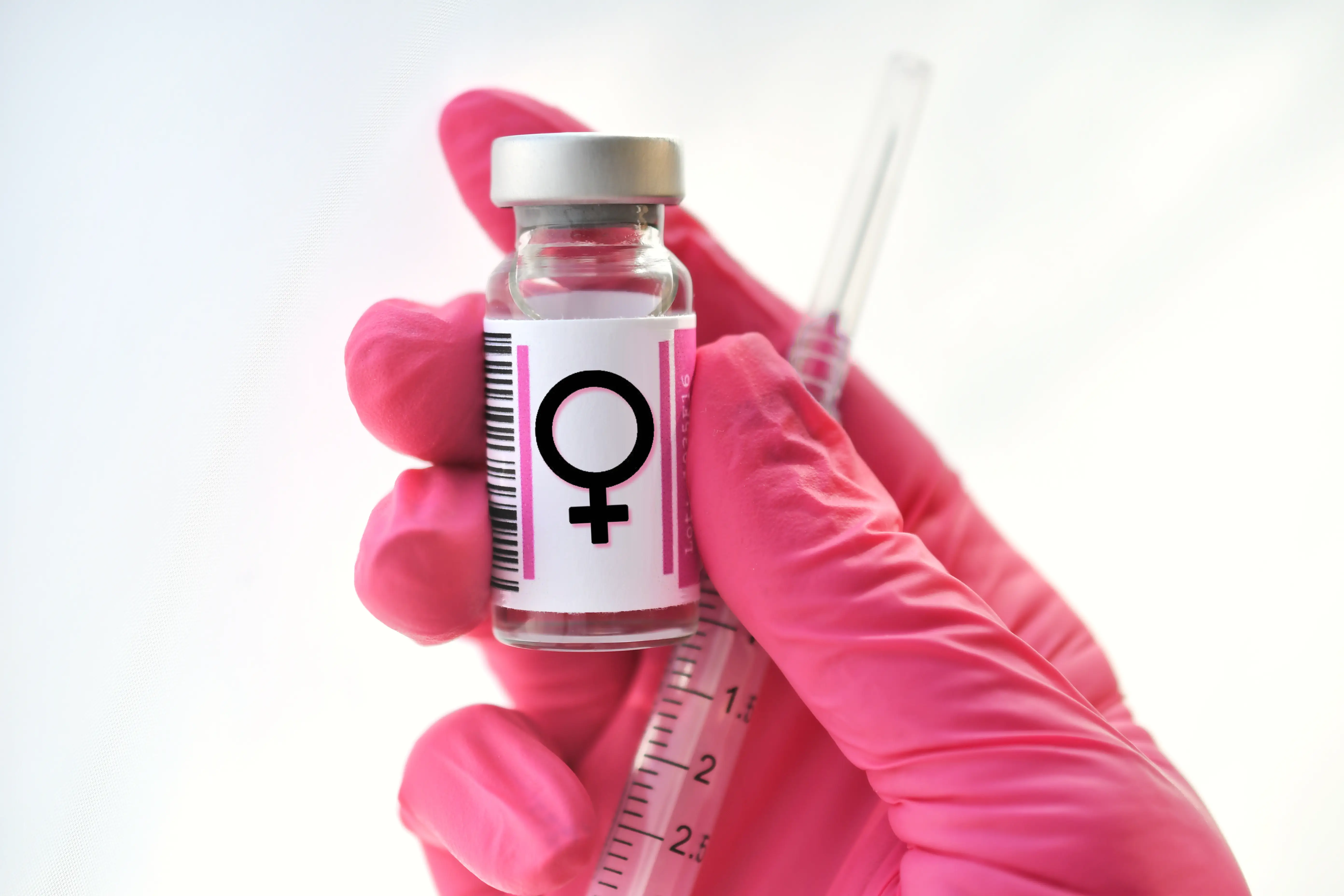 A woman smiles while holding a blister pack of medication and a glass of water indoors.